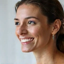 Smiling woman, mid-30s, with radiant skin and healthy glow, looking confident and happy.